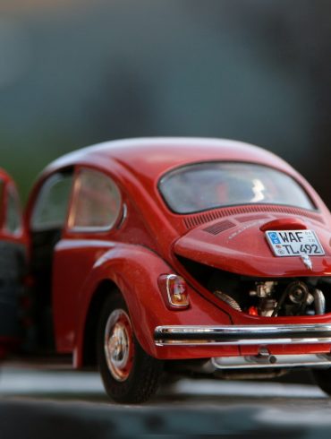 orange hair Lego toy looking at red beetle car