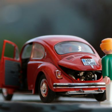 orange hair Lego toy looking at red beetle car