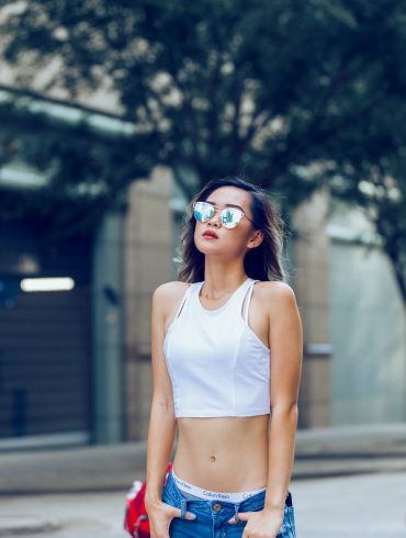woman wearing blue denim jeans and white sleeved less dress and sunglasses