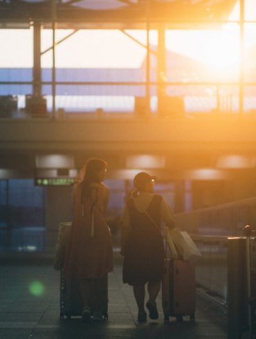 two women walking with luggage bags
