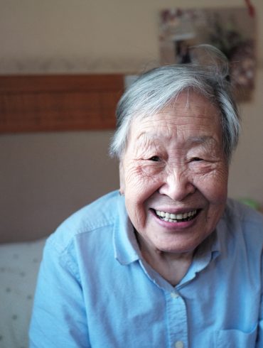 woman in blue button-down shirt smiling in front of camera