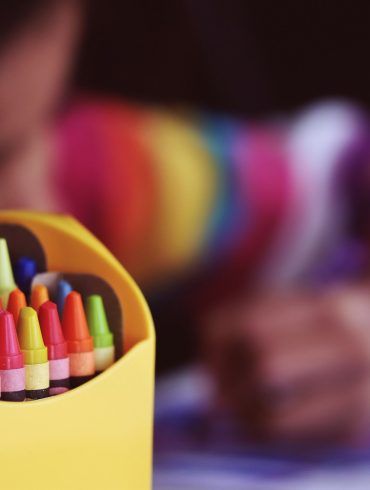 selective focal photo of crayons in yellow box