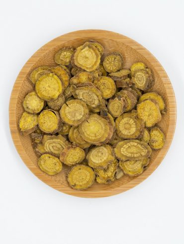 a wooden bowl filled with green vegetables on top of a white table