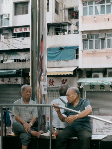 a couple of men sitting on top of a metal pole