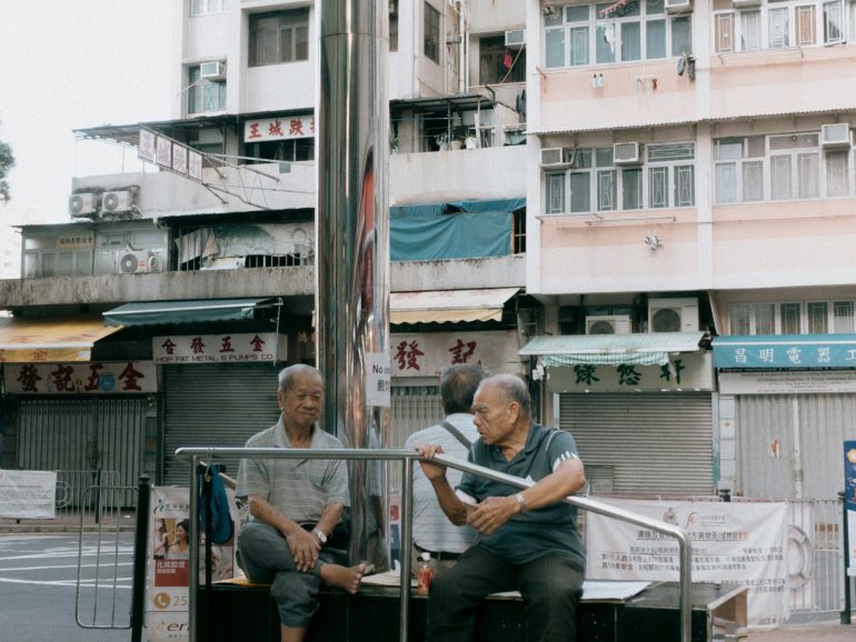 a couple of men sitting on top of a metal pole