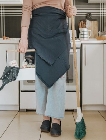a woman standing in a kitchen holding a broom