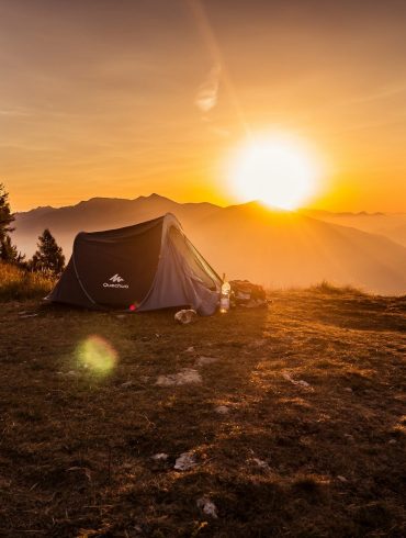 dome tent on mountain top with sun as background photo
