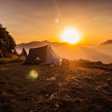 dome tent on mountain top with sun as background photo